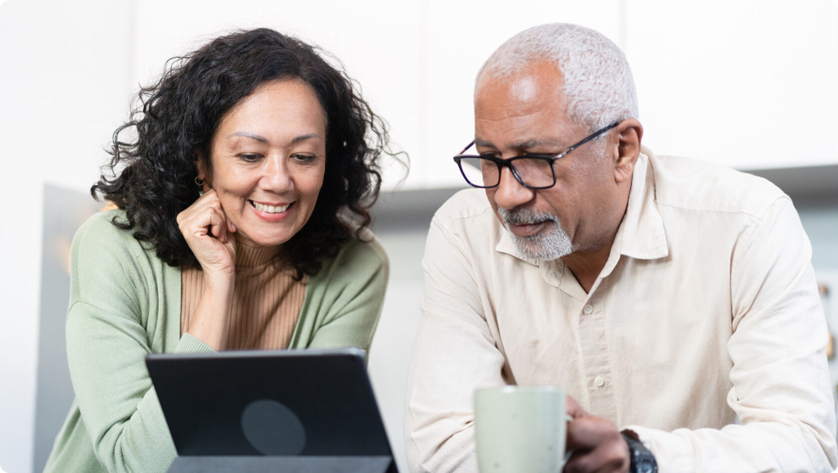 A husband and wife review information on a tablet.